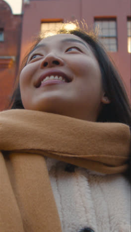 Vertical-Video-Portrait-Of-Smiling-Young-Asian-Woman-Visiting-Chinatown-In-London-UK-1